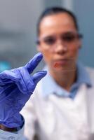 Portrait of specialist doctor analyzing blood sample test working at genetic experiment in biological biochemistry hospital laboratory. Scientist woman researching virus illness environment photo