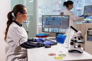 Team working to develop a new vaccine in modern equipped laboratory, typing on computer. Scientists examining vaccine evolution in medical lab using high tech, chemistry tools for scientific research. photo