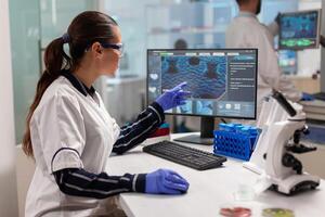 Chemical scientist conducting clinical virus research using computer. Scientists examining vaccine evolution in medical lab using high tech, chemistry tools for scientific research. photo