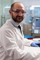 Microbiology virus researcher looking at camera in chemical lab smiling at camera. Scientist doctor examining virus evolution using high tech chemistry tools for scientific research. photo