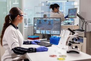 Healthcare researcher working to discover a vaccine working on computer. Scientists examining vaccine evolution in medical lab using high tech, chemistry tools for scientific research. photo