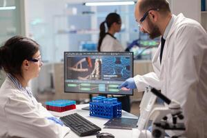 Team of microbiology scientists discussing about vaccine development in modern equipped laboratory. Chemists stuff analysing virus evolution using high tech technology for treatment research. photo