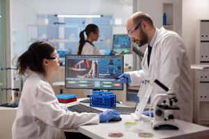 Scientist woring together to find a vaccine in healthcare lab looking at dna sample on computer. Chemists stuff analysing virus evolution using high tech technology for treatment research. photo