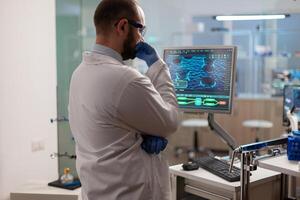 Scientist worried about virus evolution analysing DNA scan image standing, in equipped laboratory at computer. Stuff examining vaccine development using high tech researching treatment. photo