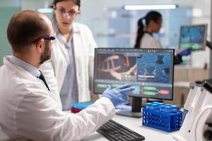 Medical team scientist conducting DNA experiments looking in computer holding test tube with blood sample. Chemists stuff analysing virus evolution using high tech technology for treatment research. photo