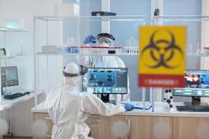 Medical staff wearing ppe suit in laboratory danger zone during pandemic. Group of doctors examining vaccine evolution using high tech for diagnosis against covid19. photo
