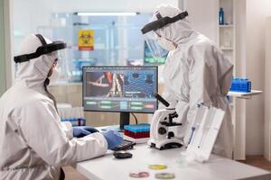 Scientists in protection suits analysing dna sample infected with virus. Team doctors working with various bacteria, tissue and blood samples, pharmaceutical research for antibiotics photo