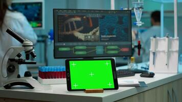 Display tablet with green screen, mock up on template placed on desk in scientific laboratory while woman medical research scientist analysing virus evolution at digital monitor conducting experiment photo