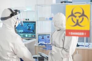 Healthcare doctors working in danger area of lab dressed in ppe suit during global pandemic. Group of doctors examining vaccine evolution using high tech for diagnosis against covid19. photo