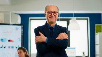 Elderly successful businessman entrepreneur standing looking at camera crossing arms and smiling. Manager working in professional start up financial business, modern company workplace ready for meeting photo