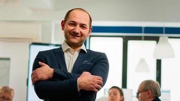 Young man project manager smiling in front of camera standing in brainstorming room, preparing for meeting with partners. Businessman working in professional start up financial business ready for conference photo