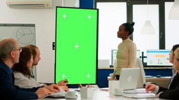 African businesswoman analysing annual financial reports standing in conference room pointing at green screen monitor. Leader explainig project strategy using greenscreen pc with chroma key display photo