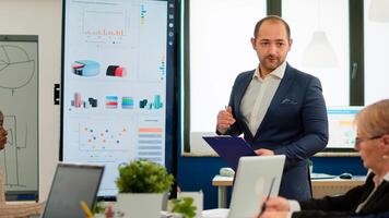 Executive manager presenting sales reports, financial evolution of start up company during conference meeting. Multiracial group of people working in boardroom discussing, briefing, planning project. photo