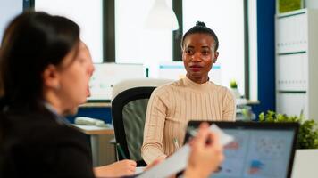 Confident african leader negotiating with business group explaining contract benefits at formal board meeting consulting corporate clients presenting commercial offer sitting at conference office table photo