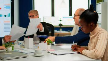 African businesswoman reading documents, signing its while business partners sharing paperwork sitting at conference table in broadroom. Executive director meeting shareholders in start up office photo