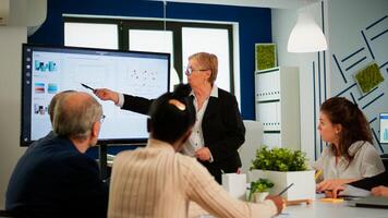 Diverse business people, staff group, sitting at desk in office, discussing about financial problems. Executive manager showing a presentation on digital interactive whiteboard with growth analysis photo