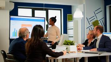 African project manager holding financial meeting showing statistical graphs and charts on interactive whiteboard touchscreen device. Executive director working in broadroom of creative agency. photo