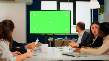 Group of business people discussing company plan with mockup tv green screen in front of desk, ready for financial project presentation. Multiethnic team using mock up monitor with chroma key display photo