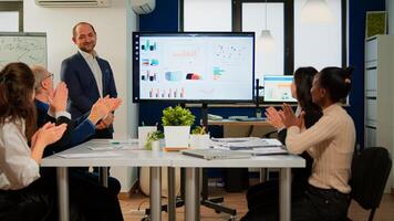 Succesful business man presenting the good evolution of company using digital interactive whiteboard with growth analysis, charts, statistics, data, Diverse people congratulate him clapping photo
