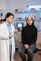 Female patient who is in a neurology clinic and her brain is being scanned. Woman sitting in lab equipped for development of experiments. Neuroscientist looking for brain trauma, nervous system. photo