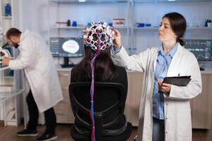 Professional doctor in neuroscience developing treatment for neurological diseases examining patient evolutions. Doctor researcher adjusting EEG headset analyzing brain functions and health status. photo
