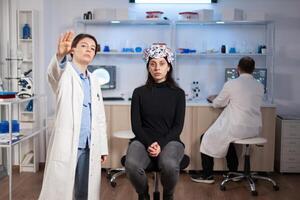 Researcher and patient with eeg headset looking at virtual display with touchscreen, virtual reality using medical inovation in neurological research lab. Scientists working with healthcare simulator. photo