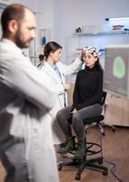 Neuroscience scientist adjusting headset with sensors on womna patient in modern lab during brain scanning. Nervous system analysis, clinic equipment. Doctor brain scan. photo