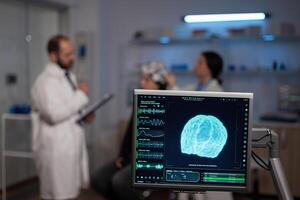 Neuroscience doctor holding clipboard showing treatment against brain disease to patient with eeg headset. Woman sitting in neurological scientific laboratory treating nervous system dysfunctions. photo