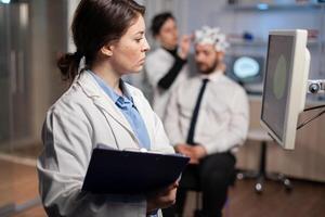 Neurologist scientist looking at brain tomography of patient with headset, high tech scan on monitor screen. Doctor adjunsting electrodes. Modern neuroscience. photo