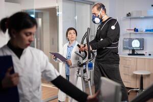 Performance athlete testing endurace in sports laboratory, running with electrodes on body for monitoring. Measuring heart rate cardio examination cross. photo