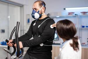Sport researcher in test examination of athlete performance, monitoring, electrodes on body, running heart rate cardio. Body endurance analyzing sensors equipment machine, sportman. photo