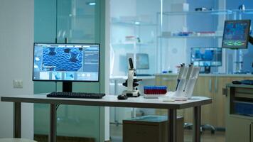 Modern empty biological applied science laboratory with technological microscopes, glass test tubes, micropipettes, desktop computers and displays. PC's are running sophisticated DNA calculations. photo