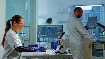 Team working to develop a new vaccine in modern equipped laboratory, woman typing at computer. Group of biochemistry scientists examining virus evolution using high tech for researching treatment photo