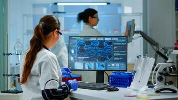 Laboratory doctor holding at blood sample and writing on computer while coworker opening door using digital computer with touch scan. Woman examining virus evolution using high tech and chemistry tools photo