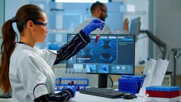 Scientist doctor looking at blood sample and typing on computer while coworker opening door using digital computer with touch scan. Woman examining virus evolution using high tech and chemistry tools photo
