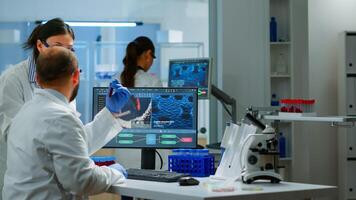 Group of scientists working in modern equipped laboratory pointing on computer desktop. Team of doctors examining vaccine evolution using high tech researching diagnosis against covid19 virus photo