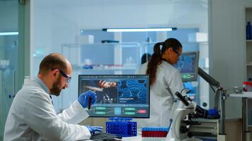 Laboratory medical stuff disscussing about vaccine development holding test tube with blood sample. Medical scientist working with DNA scan image in modern equipped laboratory using high tech photo