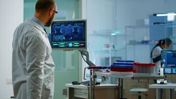 Scientist worried about virus evolution analysing DNA scan image standing in equipped laboratory typing at computer. Stuff examining vaccine development using high tech researching treatment photo