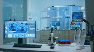 Modern empty research applied science laboratory with technological microscopes, glass test tubes, micropipettes, desktop computers and displays. PC's are running sophisticated DNA calculations. photo