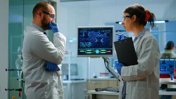 Team of chemists working with DNA scan image looking at desktop standing in medical research laboratory, analysing biochemicals samples, talking. Microbiology development with advanced equipment photo