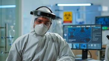 Close up of tired chemist doctor in coverall looking at camera working in scientific laboratory. Scientist working with various bacteria, tissue and blood samples, pharmaceutical research for antibiotics photo