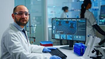 Experienced medical lab practitioner smiling and looking in camera. Team of scientists doctors examining virus evolution using high tech and chemistry tools for scientific research, vaccine photo