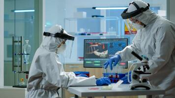 Doctor with coverall working with blood samples in laboratory typing on pc. Team of chemists examining vaccine evolution using high tech for research in treatment development against covid19 virus photo