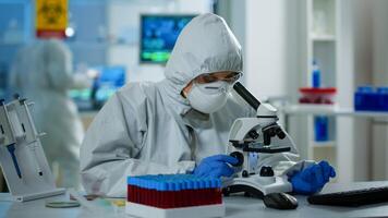 Woman scientist in ppe suit working in lab using modern microscope with slides. Team of chemists researcher examining virus evolution using high tech for vaccine scientific research against covid19 photo