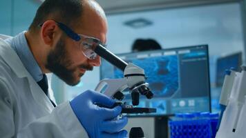 Lab technician examining samples and liquid using microscope in equipped laboratory. Scientist working with various bacteria, tissue and blood samples, pharmaceutical research for antibiotics photo