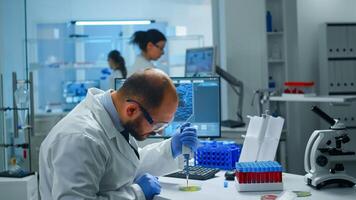 Scientist in medical laboratory examining drug discovery putting blood sample in petri dish with micropipette. Biochemist analysing virus evolution using high tech researching vaccine against covid19 photo