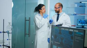Team of medical scientists conducting vaccine development with help of high tech, doctor holding tablet analysing new informations. Examining virus evolution using devices researching diagnosis photo
