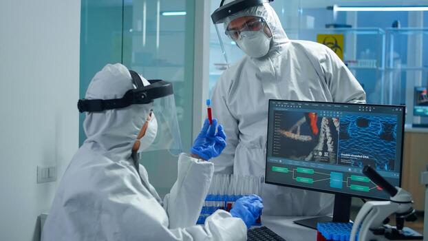 Professional chemists in ppe suit analysing vaccine development pointing on pc display in equipped laboratory. Scientist examining virus evolution using high tech researching diagnosis against covid19 photo