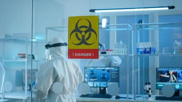 Scientist team in protective suit preparing tools for analysing virus development in danger zone of laboratory. Team of scientists analysing vaccine evolution using high tech for researching treatment photo