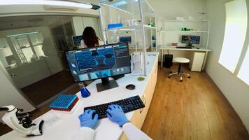 POV of team working to develop a new vaccine in modern equipped laboratory, man typing at computer. Group of biochemistry scientists examining virus evolution using high tech for researching treatment photo